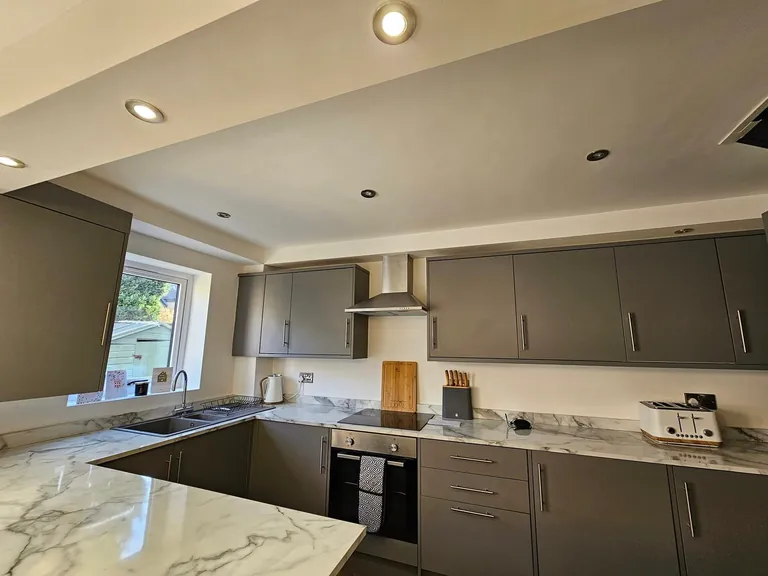 Grey kitchen cabinets with pale painted walls and a white ceiling