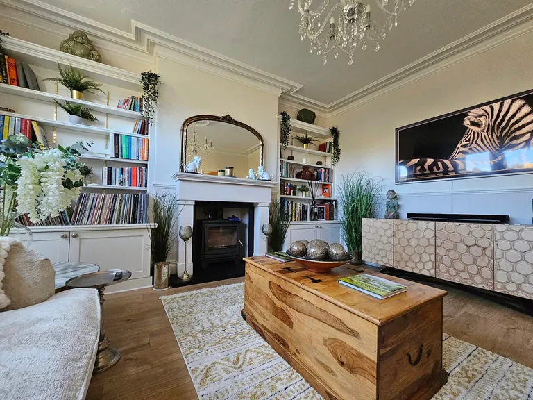 Living room with cream walls, white alcove shelving and a dark fireplace