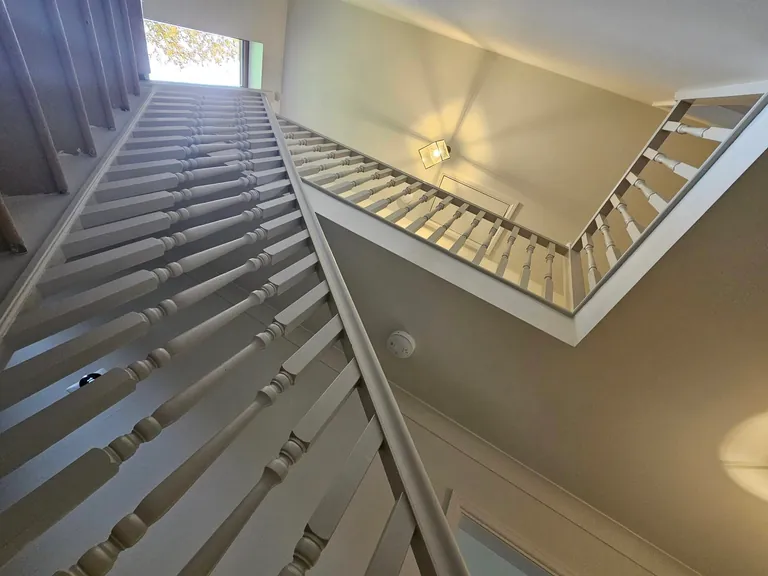 Tall stairwell with white spindles and neutral painted walls