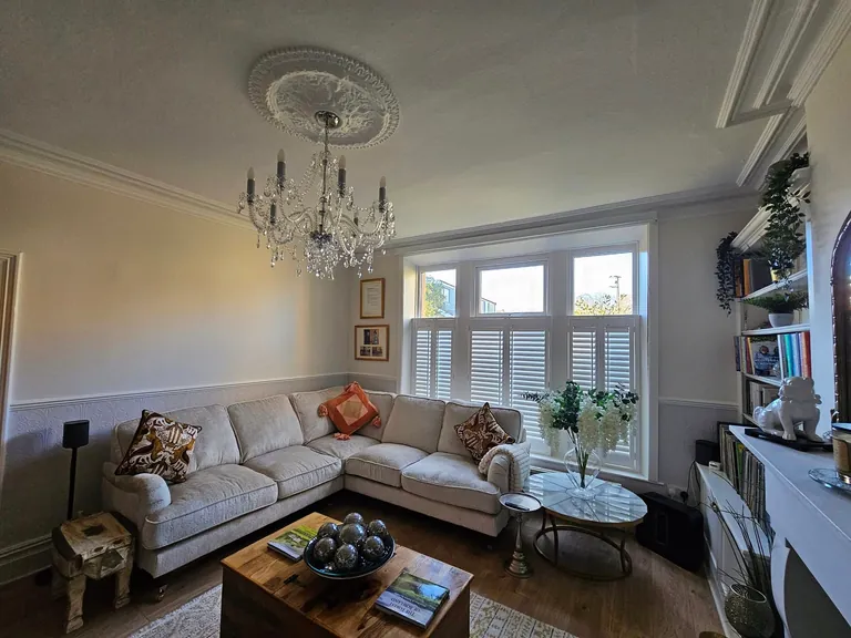 Decorated living room with neutral walls, ceiling cornice and a chandelier